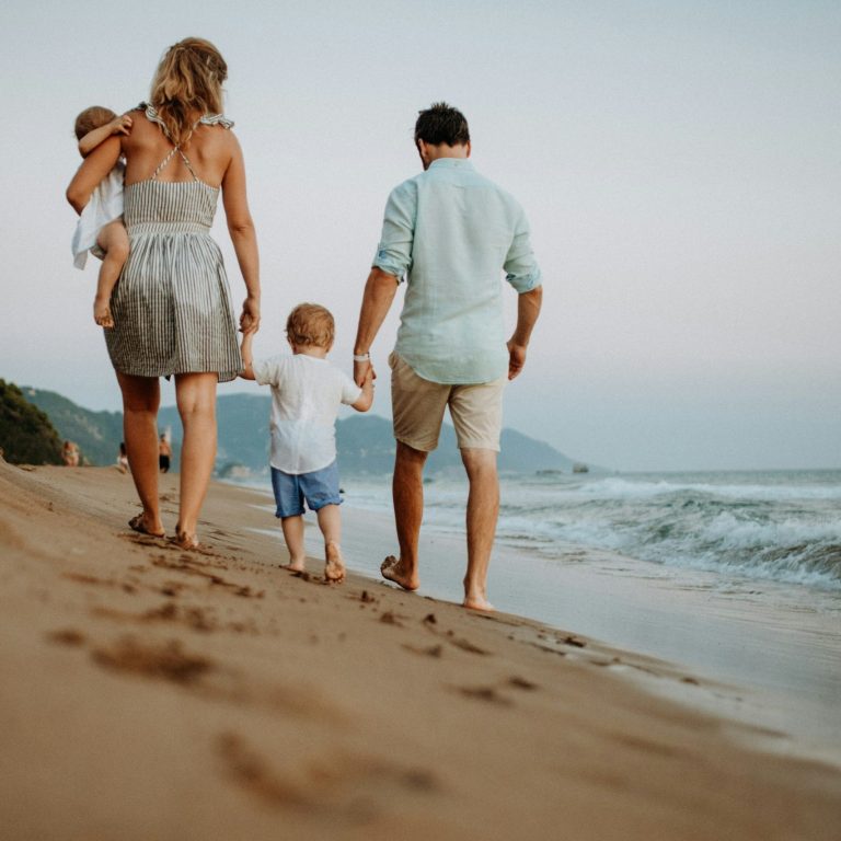 Family Beach Holidays Family walking together on a beach during their holiday